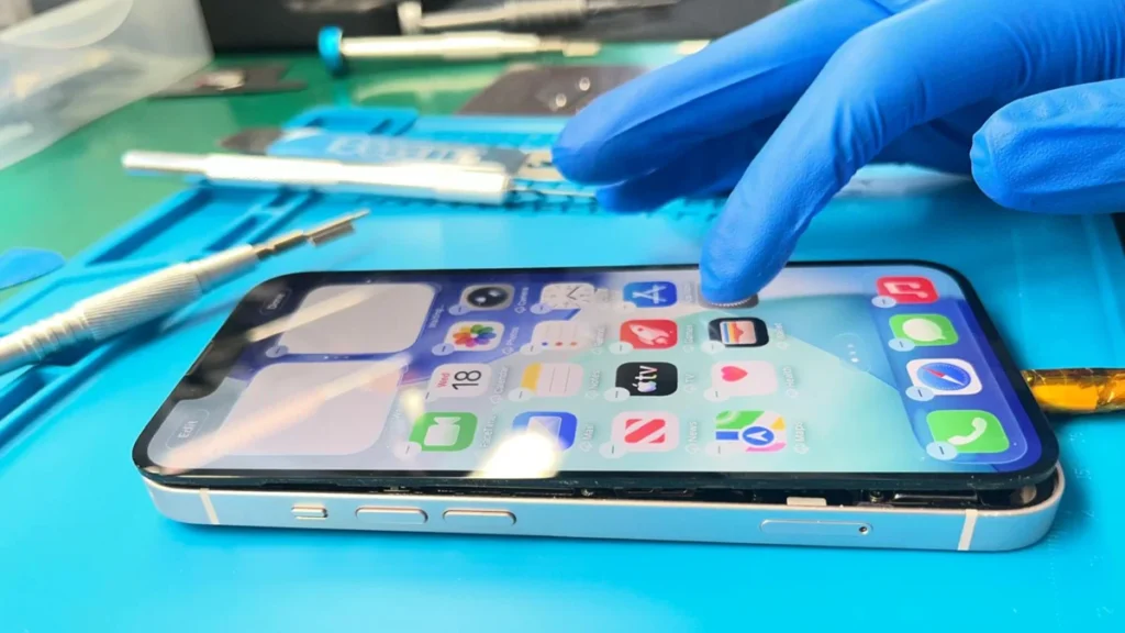 iPhone encendido con pantalla sin pegar, técnico verificando