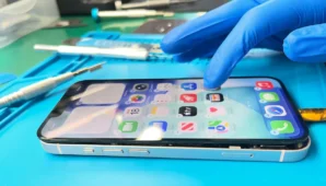 iPhone encendido con pantalla sin pegar, técnico verificando
