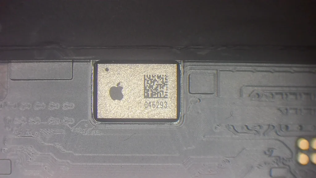 IC táctil original de iPhone visto bajo microscopio — chip serializado que causa el aviso Pieza Desconocida