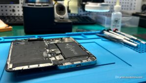 Un iPhone abierto sobre el banco de reparación de Preciosadictos, con la batería a la vista